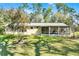 Charming home featuring a screened-in porch, metal roof, and a well-maintained lawn, surrounded by mature trees at 53722 Rivertrace Rd, Astor, FL 32102