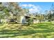 A well-manicured lawn and screened-in porch highlight this home's backyard, surrounded by trees and under a blue sky at 53722 Rivertrace Rd, Astor, FL 32102