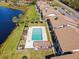 Aerial view of a community pool, clubhouse, and lake with palm trees next to apartment buildings at 542 Belltower Ave, Deltona, FL 32725