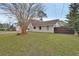 Well-kept home featuring green grass, trimmed trees, and a fence, creating a beautiful and private yard at 605 Anderson Dr, Deltona, FL 32725