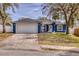This home has a two-car garage, inviting front porch, and a driveway framed by mature trees at 711 Hiview Cir, Port Orange, FL 32127