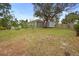 Grey single-story house with a shed and fenced-in backyard, under a large tree, with foliage and grass at 1576 Naples Cir, Deltona, FL 32738