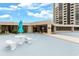 Exterior shot of building entrance with an umbrella, seating, and manicured greenery at 1 Oceans West Blvd # 1B2, Daytona Beach, FL 32118