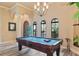 Well-lit game room with a pool table, arched windows, and an elegant chandelier at 100 Via Rosa Ct, Debary, FL 32713