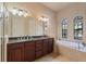 Main bathroom featuring dark wood cabinets, double sinks, a soaking tub, and natural light at 100 Via Rosa Ct, Debary, FL 32713