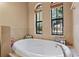 Main bathroom featuring a large tub, tile surround, and two windows providing natural light at 100 Via Rosa Ct, Debary, FL 32713