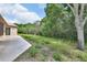 Backyard with large tree on left, lush greenery, and view of rear of neutral colored home at 1491 W Silver Hammock, Deland, FL 32720