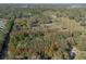 The property with red boundary lines sits among trees near other open lots, a neighboring residential area nearby at 1712 Alanson Dr, Deland, FL 32724