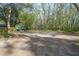 A tranquil backyard featuring mature trees and sandy ground, offering privacy and shade for relaxation at 1712 Alanson Dr, Deland, FL 32724