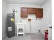 Inside laundry room includes utility sink, washer and dryer hookups, and overhead storage cabinets at 1712 Alanson Dr, Deland, FL 32724