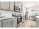 Modern kitchen features stainless steel appliances, gray cabinets, white subway tile backsplash, and wood-look tile floors at 1716 Red Rock Rd, New Smyrna Beach, FL 32168