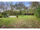 Spacious backyard featuring a mix of grassy areas, mature trees, and versatile outbuildings at 1930 S Clara Ave, Deland, FL 32720