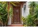 An ornate wood front door framed by lush landscaping creates a grand entrance at 201 Ocean Shore Blvd, Ormond Beach, FL 32176