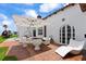 Inviting brick patio featuring an umbrella, modern seating, and views of the white house exterior with arch door at 201 Ocean Shore Blvd, Ormond Beach, FL 32176