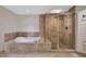 Bathroom showcasing a soaking tub, glass-enclosed shower, and travertine tile at 231 Riverside Dr # 1801-1, Daytona Beach, FL 32117