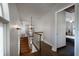 Bright hallway with hardwood steps, sconce lighting, chandelier, and wood-look floors leading to bedrooms at 2852 John Anderson Dr, Ormond Beach, FL 32176