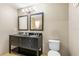 Bathroom with a black vanity with double sinks, decorative mirrors, a toilet, and neutral tones at 3346 Pegaso Ave, New Smyrna Beach, FL 32168