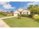 Landscaped front yard of a single-story home featuring a lush lawn, palm trees, and a driveway at 347 Admiralty Ct, Edgewater, FL 32141