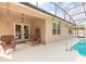 A covered pool area with lounge chairs, seating, and an access door to the residence at 347 Admiralty Ct, Edgewater, FL 32141