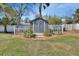 Backyard shed with double doors, small windows, surrounded by a decorative white fence, and a tidy mulch bed at 435 N Oak Ave, Orange City, FL 32763