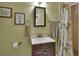 Well-lit bathroom with a white basin, framed artwork, and a bamboo shower curtain at 435 N Oak Ave, Orange City, FL 32763