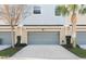 Three gray garage doors on a townhome featuring a palm tree and small landscaping in front at 471 Portico Ct, Oviedo, FL 32765
