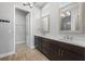 Bright bathroom featuring double vanity, elegant mirrors, and wood look tile flooring leading to a walk in closet at 6263 W Fallsgrove Ln, Port Orange, FL 32128
