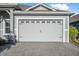 Close-up of the attached two-car garage featuring decorative windows and a paved driveway at 6263 W Fallsgrove Ln, Port Orange, FL 32128