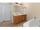 Bright bathroom features a double sink vanity, wood-look tile floors, and a soaking tub at 707 Leeward Dr, Deltona, FL 32738
