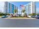 Condominium building exterior with palm trees and American flag, showing mature landscaping and parking at 925 N Halifax Ave # 910, Daytona Beach, FL 32118