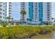 Exterior view of a high-rise building, with a pool and landscaping visible, highlighting its amenities at 925 N Halifax Ave # 910, Daytona Beach, FL 32118