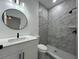 Modern bathroom with white vanity, round mirror, and a tiled shower with contemporary fixtures at 955 Redwood St, Daytona Beach, FL 32117