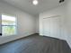 Bright bedroom with a large window, closet, and gray, wood-look floors at 955 Redwood St, Daytona Beach, FL 32117