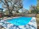 Sparkling pool surrounded by mature trees and a brick fireplace feature in the backyard at 1002 Charles St, Port Orange, FL 32129