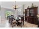 Refined dining space with travertine tile, glass table, dark-wood hutch, and elegant chandelier at 1058 W Seagate Dr, Deltona, FL 32725