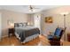 Comfortable bedroom with hardwood floors, ceiling fan, rocking chair and a queen size bed at 1062 Golf View Estates Dr, Orange City, FL 32763
