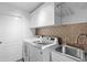 Well-lit laundry room features front loading washer and dryer and custom tile backsplash at 1062 Golf View Estates Dr, Orange City, FL 32763
