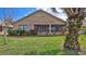 Backyard view of a brick home features a cozy screened patio, greenery and a palm tree at 111 Brown Crane Ct, Daytona Beach, FL 32119