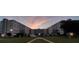 Exterior view of condo complex featuring manicured lawn and palm trees at dusk at 1224 S Peninsula Dr # 210, Daytona Beach, FL 32118