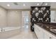 Elegant bathroom with a soaking tub, granite countertops, and floral accent wall at 1900 N Atlantic Ave # 504, Daytona Beach, FL 32118