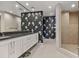 Well-lit bathroom with a walk-in shower, floral accent wall, and granite countertops at 1900 N Atlantic Ave # 504, Daytona Beach, FL 32118