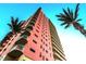 Towering exterior view of a high-rise building with multiple balconies and palm trees against a bright blue sky at 1900 N Atlantic Ave # 504, Daytona Beach, FL 32118