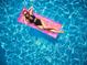 Aerial view of a Personal relaxing on a pink raft in a sparkling blue pool with sunlight reflecting off the water at 1900 N Atlantic Ave # 504, Daytona Beach, FL 32118