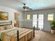 Staged bedroom with french doors, ceiling fan, metal bed frame and earth-tone color scheme at 1990 Spruce Creek N Cir, Port Orange, FL 32128