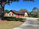 Brick exterior with a three-car garage and a long driveway at 1990 Spruce Creek N Cir, Port Orange, FL 32128