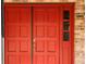 Close-up of a bold red front door with sidelight, complemented by the brick exterior of the home at 1990 Spruce Creek N Cir, Port Orange, FL 32128