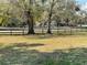 Large front yard with mature trees and dark wood fence surrounding the property at 1990 Spruce Creek N Cir, Port Orange, FL 32128