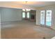 Spacious, empty living room with a fireplace, French doors, and neutral carpet at 1990 Spruce Creek N Cir, Port Orange, FL 32128
