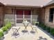 Cozy patio seating with chairs and a small table, surrounded by well-maintained landscaping and a red brick home at 1990 Spruce Creek N Cir, Port Orange, FL 32128