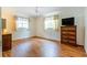 Bedroom featuring wood-look floors, two windows with curtains, and a vintage dresser at 28 W Highbanks Rd, Debary, FL 32713